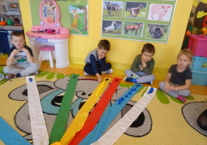 Dzieci układają kolorowe misie zgodnie z liczbą na wstążce wiatraka.